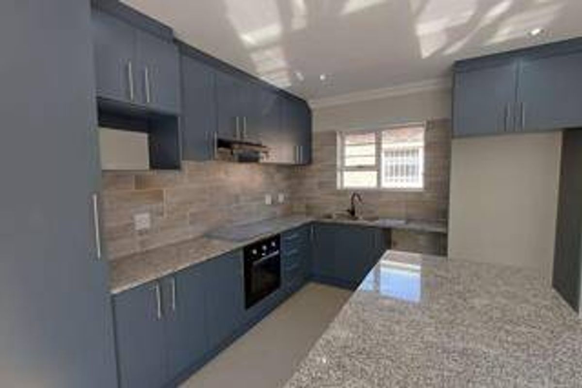 Modern kitchen featuring dark blue cabinetry, granite countertops, tiled backsplash, built-in oven, and an integrated breakfast island.