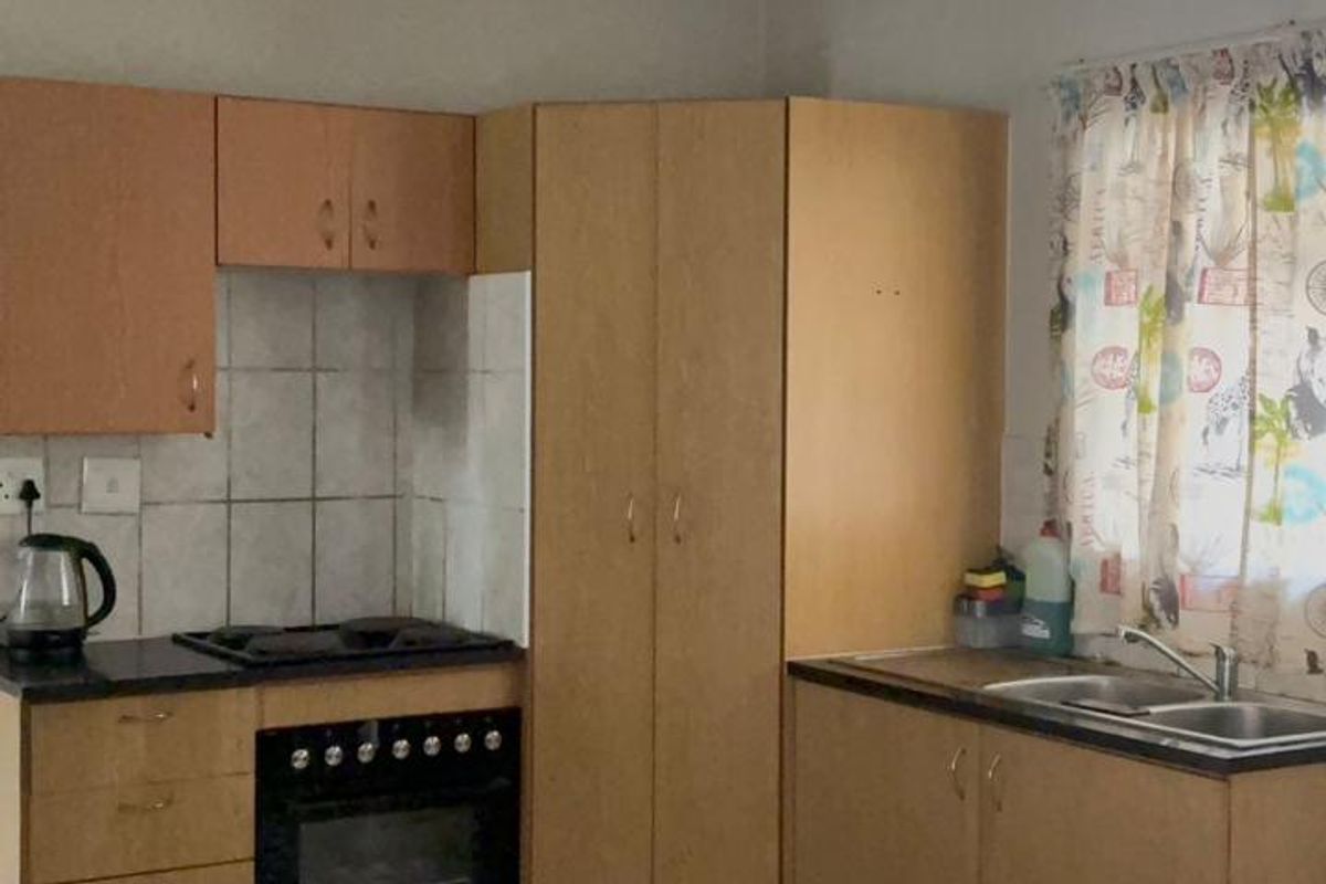 A functional kitchen featuring built-in cabinetry, a built-in oven with hob, double bowl sink, and tiled flooring, offering a practical layout for daily use.