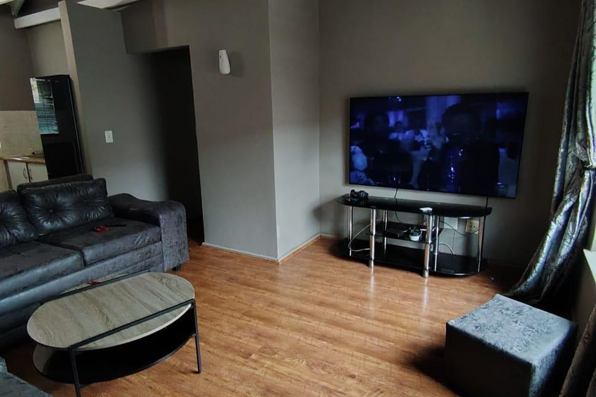 Spacious living room featuring high vaulted ceilings with exposed white trusses and durable laminate flooring.