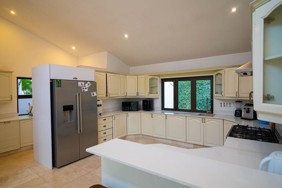 Spacious kitchen featuring cream-toned cabinetry, stone countertops, a gas hob with extractor, and tiled flooring, offering a functional layout with ample storage.