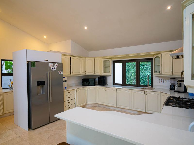 Spacious kitchen featuring cream-toned cabinetry, stone countertops, a gas hob with extractor, and tiled flooring, offering a functional layout with ample storage.