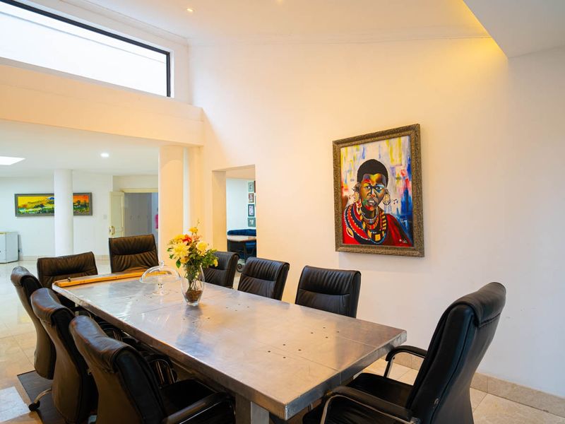 Spacious dining area featuring high ceilings, clerestory windows for natural light, and polished tile flooring, creating an open and airy atmosphere.