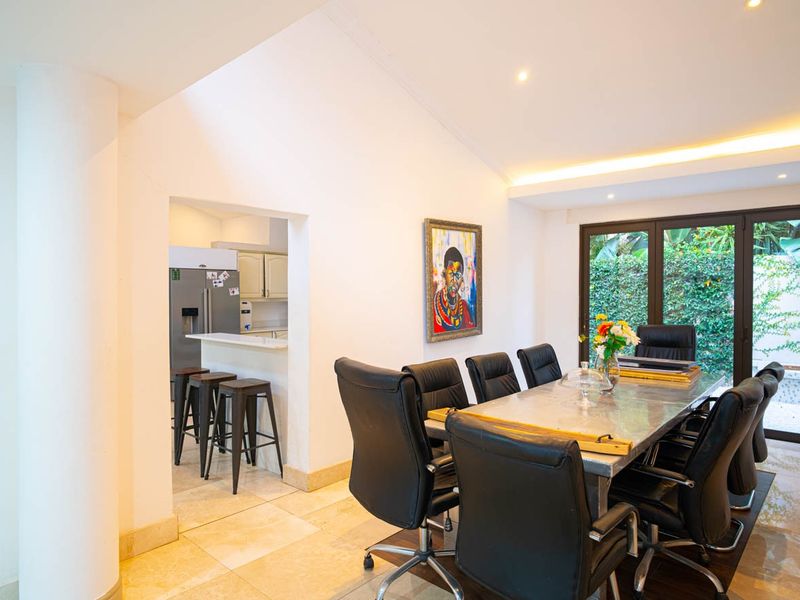 Spacious open-plan dining area featuring stone flooring, recessed lighting, and direct access to the garden through large sliding glass doors.