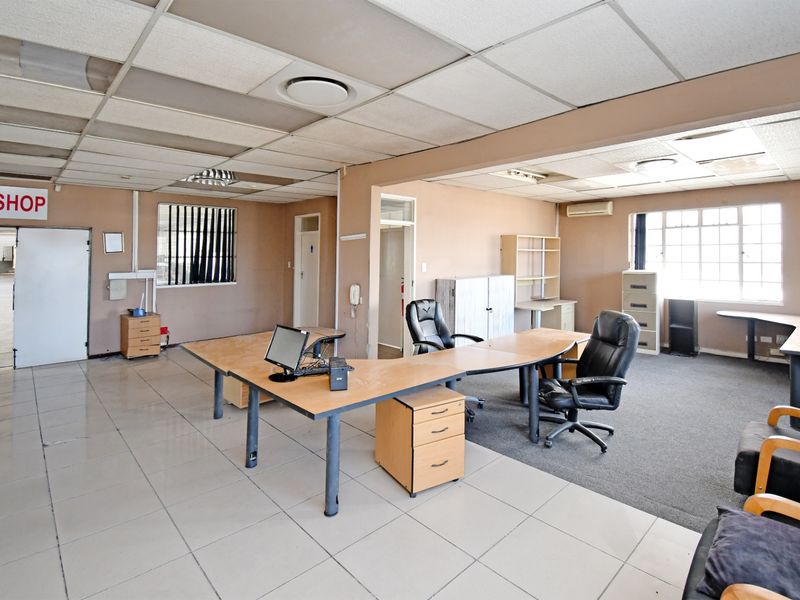 Spacious industrial office area featuring a mix of tiled and carpeted flooring, suspended ceiling with recessed lighting, and integrated air conditioning.