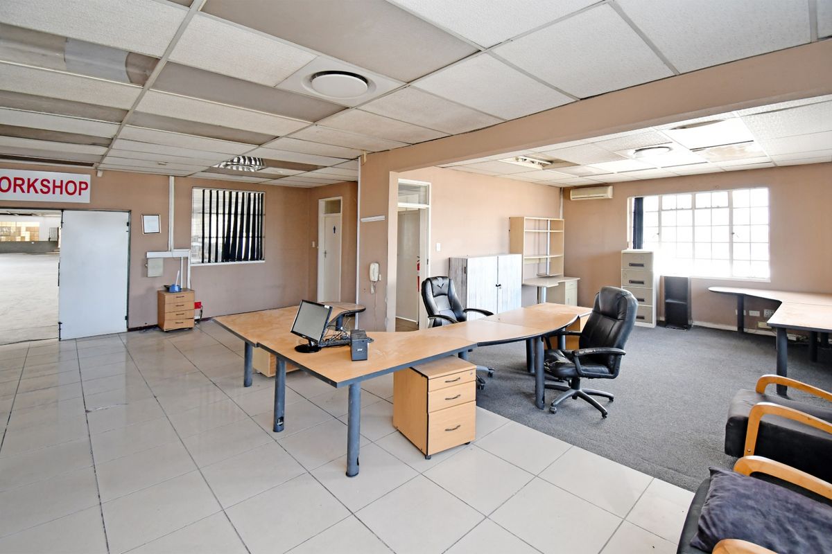 Spacious industrial office area featuring a mix of tiled and carpeted flooring, suspended ceiling with recessed lighting, and integrated air conditioning.