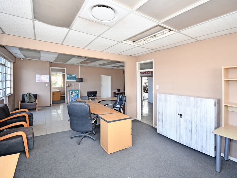 Spacious industrial office area featuring a mix of carpeted and tiled flooring, suspended ceiling, and integrated air conditioning.