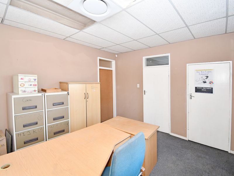 A functional office space featuring a suspended ceiling, recessed lighting, and multiple internal doors, currently utilized as a workspace.