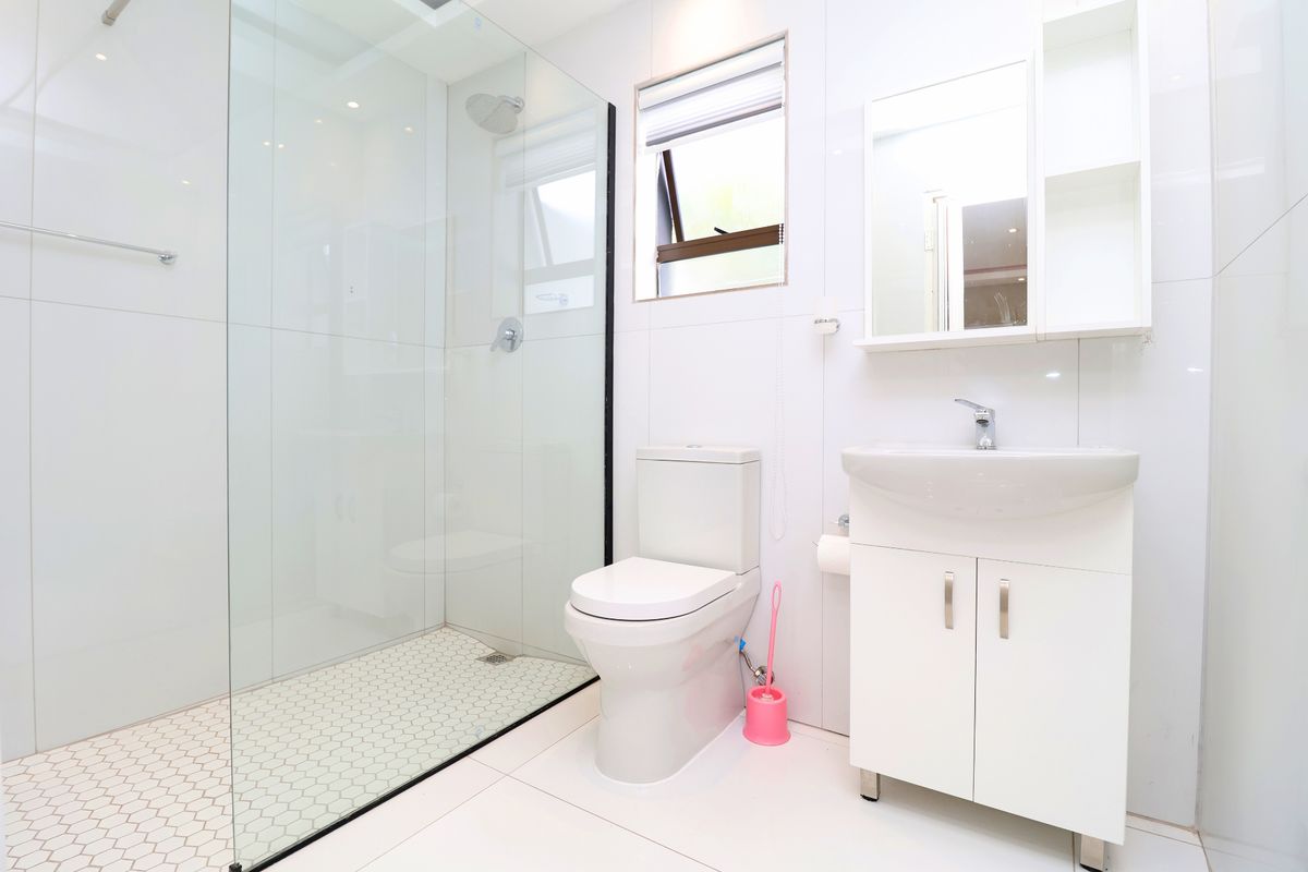 Modern, well-maintained bathroom featuring a glass-enclosed shower, white vanity with basin, and clean tiled finishes throughout.