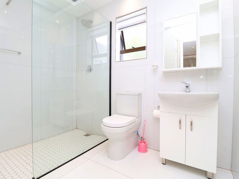 Modern, well-maintained bathroom featuring a glass-enclosed shower, white vanity with basin, and clean tiled finishes throughout.