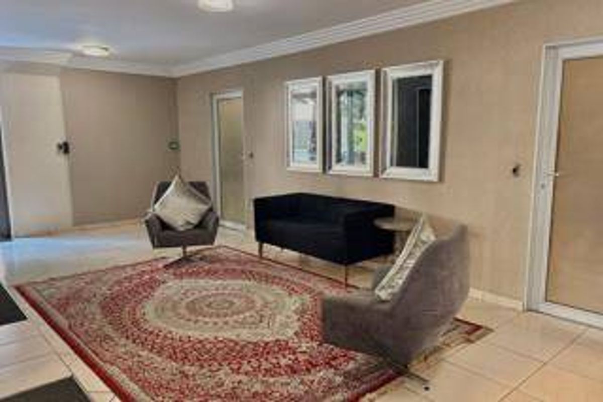 A well-maintained living room featuring neutral wall tones, tiled flooring, and recessed ceiling lighting, providing a clean and functional space.