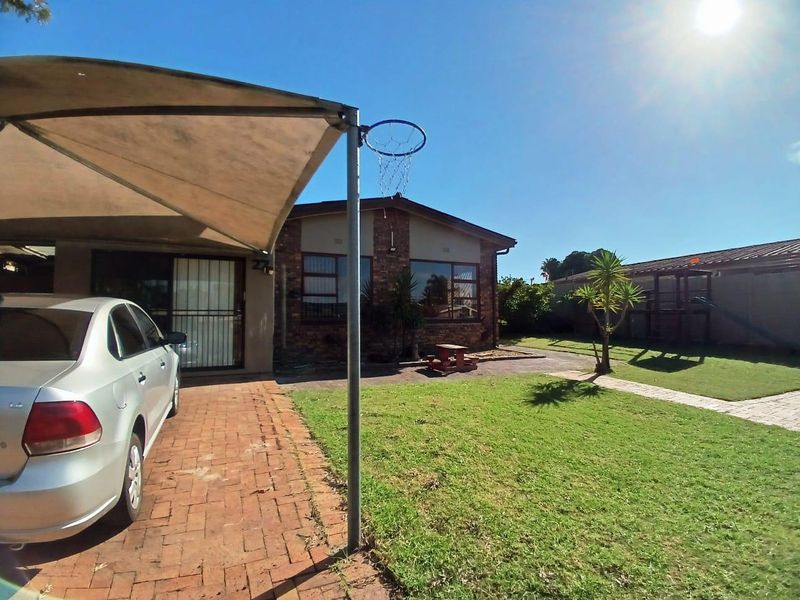 Front exterior view of the property featuring a brick driveway, shade sail, and a well-maintained lawn area.