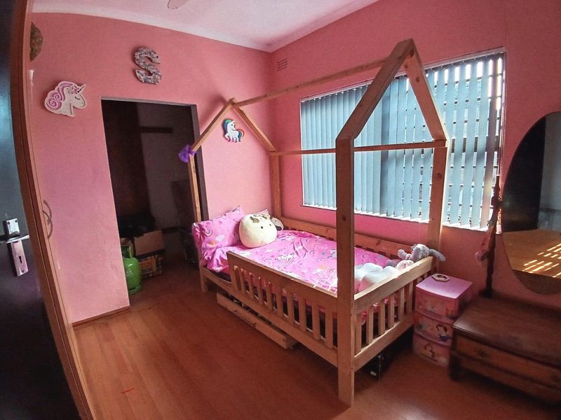 A bedroom featuring laminate flooring, vertical blinds, and a ceiling fan, currently decorated as a child's room.
