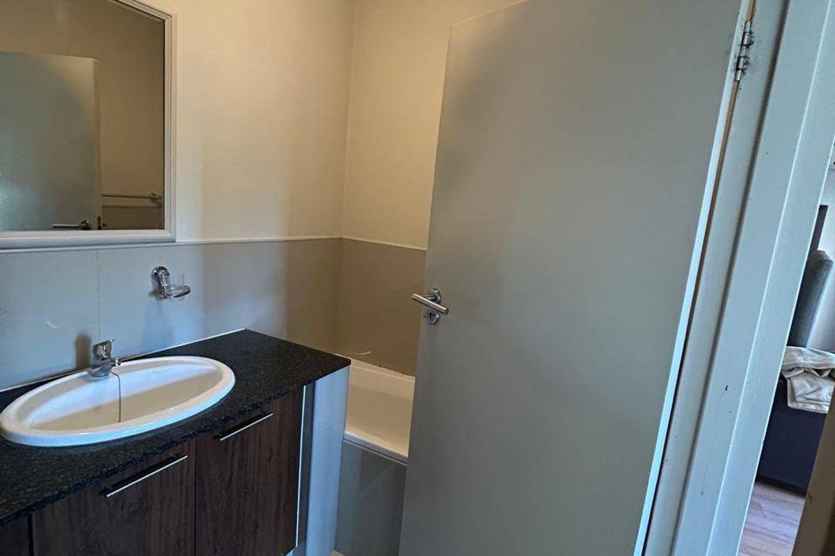 A clean, functional bathroom featuring a dark wood vanity with a granite countertop, drop-in basin, and a built-in bathtub.