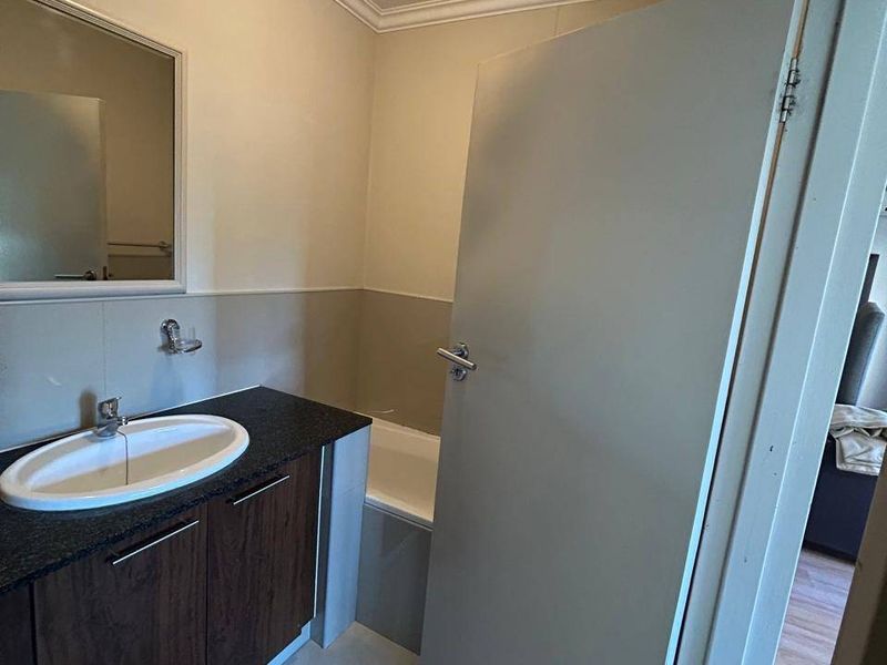 A clean, functional bathroom featuring a dark wood vanity with a granite countertop, drop-in basin, and a built-in bathtub.