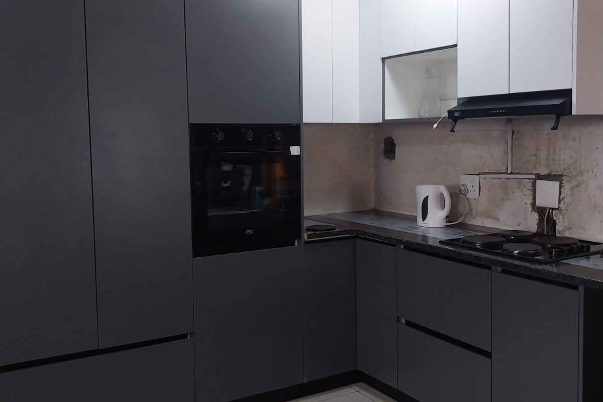 Modern kitchen featuring a two-tone grey and white cabinetry design, built-in oven, and hob, requiring final finishing touches to the wall surfaces.