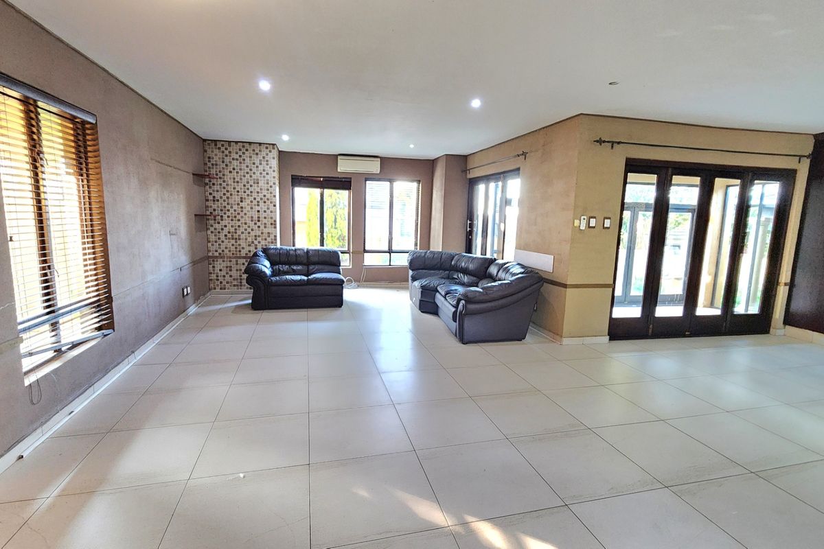 Spacious living area featuring large format floor tiles, recessed lighting, a split-system air conditioner, and direct access to the outdoor area through sliding doors.