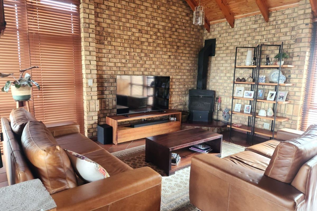 Cozy living room featuring exposed brick walls, a vaulted timber ceiling, and a built-in wood-burning fireplace, creating a warm and inviting atmosphere.