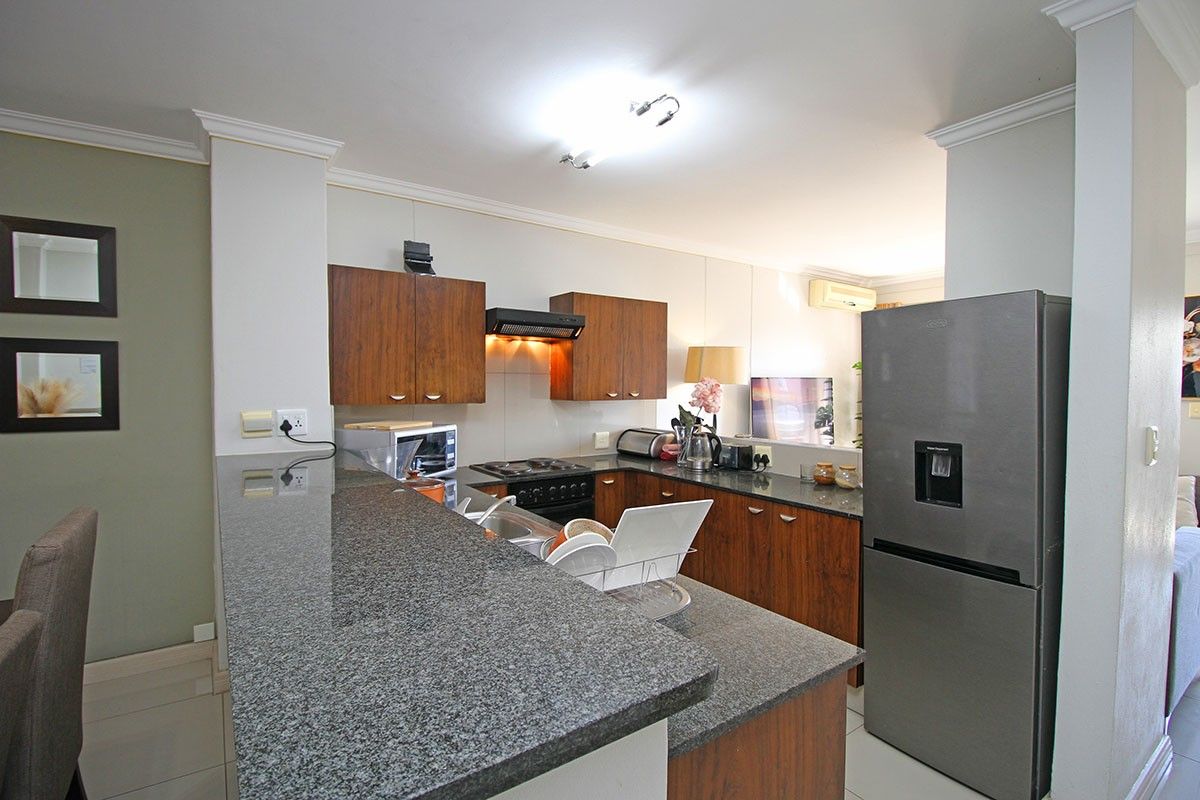 A functional kitchen featuring granite countertops, wood-finish cabinetry, and integrated appliances, seamlessly connected to the living area.