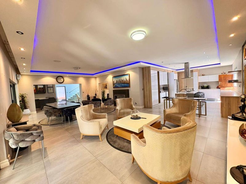 Spacious open-plan living, dining, and kitchen area featuring modern recessed lighting, tiled floors, and a sleek kitchen island with integrated appliances.