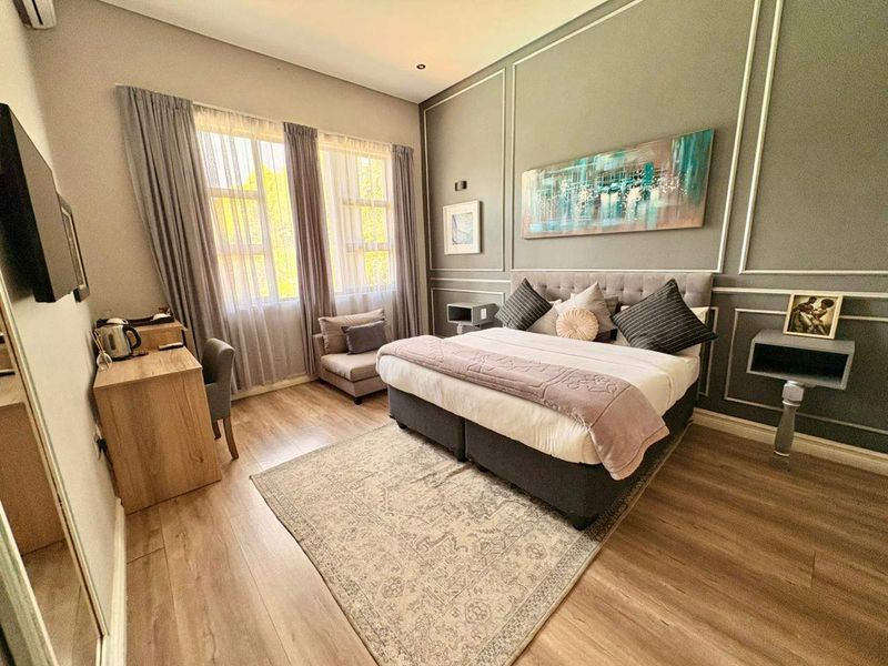 A well-maintained bedroom featuring laminate flooring, decorative wall molding, and an integrated air conditioning unit.