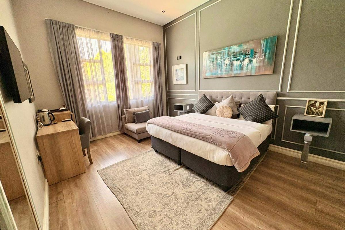 A well-maintained bedroom featuring laminate flooring, decorative wall molding, and an integrated air conditioning unit.