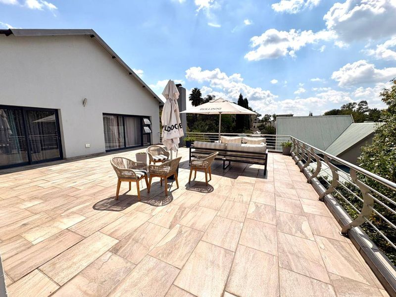 Spacious outdoor balcony featuring tiled flooring and a modern stainless steel balustrade, providing an open-air entertainment area with access to the main dwelling.