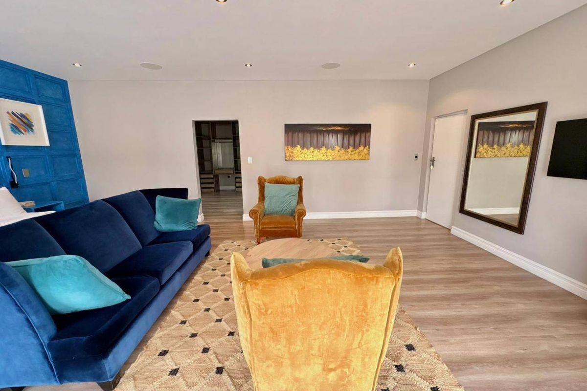 Spacious living room featuring modern laminate flooring, recessed downlighting, and direct access to a walk-in closet area.