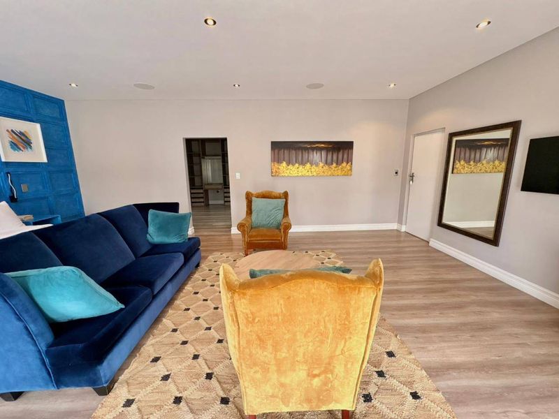 Spacious living room featuring modern laminate flooring, recessed downlighting, and direct access to a walk-in closet area.