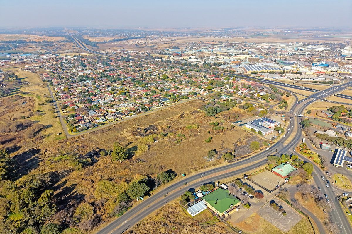 An aerial view showing the surrounding residential neighborhood, road networks, and commercial infrastructure in proximity to the vacant land.