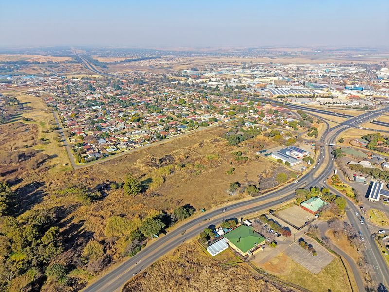 An aerial view showing the surrounding residential neighborhood, road networks, and commercial infrastructure in proximity to the vacant land.