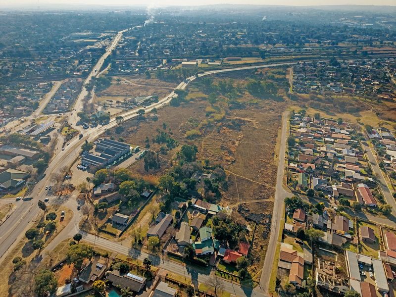 An aerial view of a large vacant residential plot situated within an established suburban neighborhood with access to local road networks.