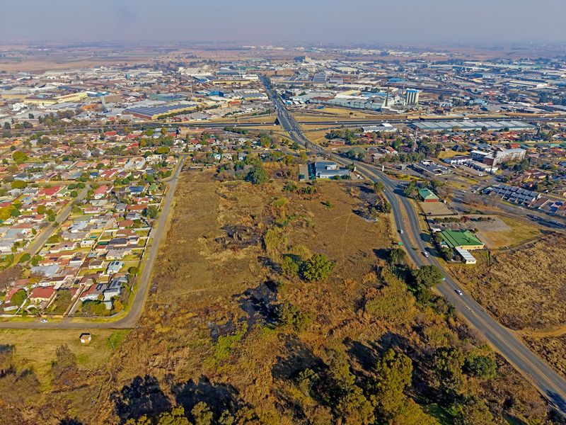 Aerial view of a large vacant residential plot situated within an established suburban and industrial area with direct road access.