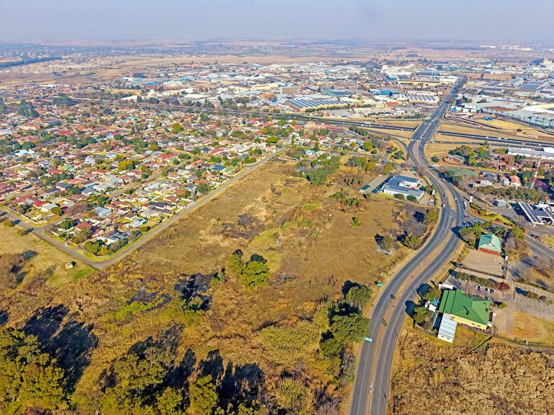 An aerial view of a vacant residential land parcel situated near established suburban housing and commercial infrastructure.