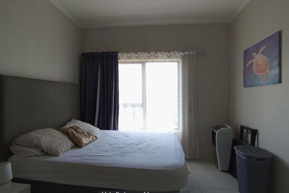 A functional bedroom featuring tiled flooring, neutral wall finishes, and a large window allowing for natural light.