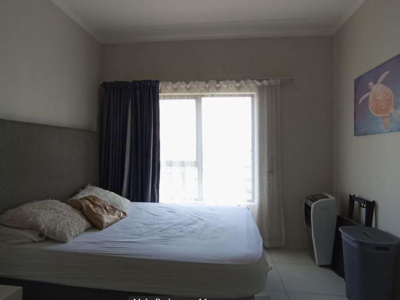 A functional bedroom featuring tiled flooring, neutral wall finishes, and a large window allowing for natural light.