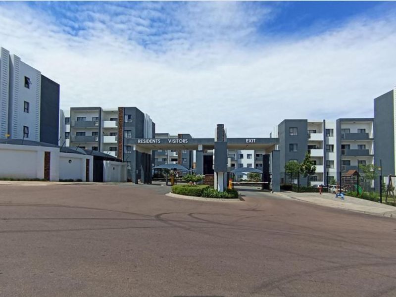 The main entrance and security gatehouse of the apartment complex, featuring controlled access points for residents and visitors.