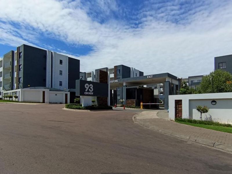 The main entrance and security gatehouse of the 93 On New apartment complex, featuring modern architecture and paved access.