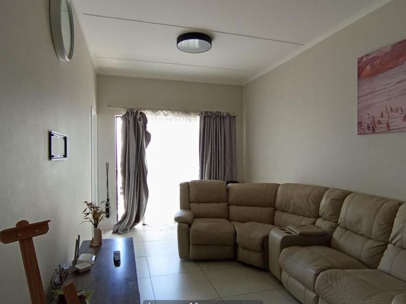 A comfortable living room featuring neutral tiled flooring and a sliding glass door that provides access to the outdoor area.