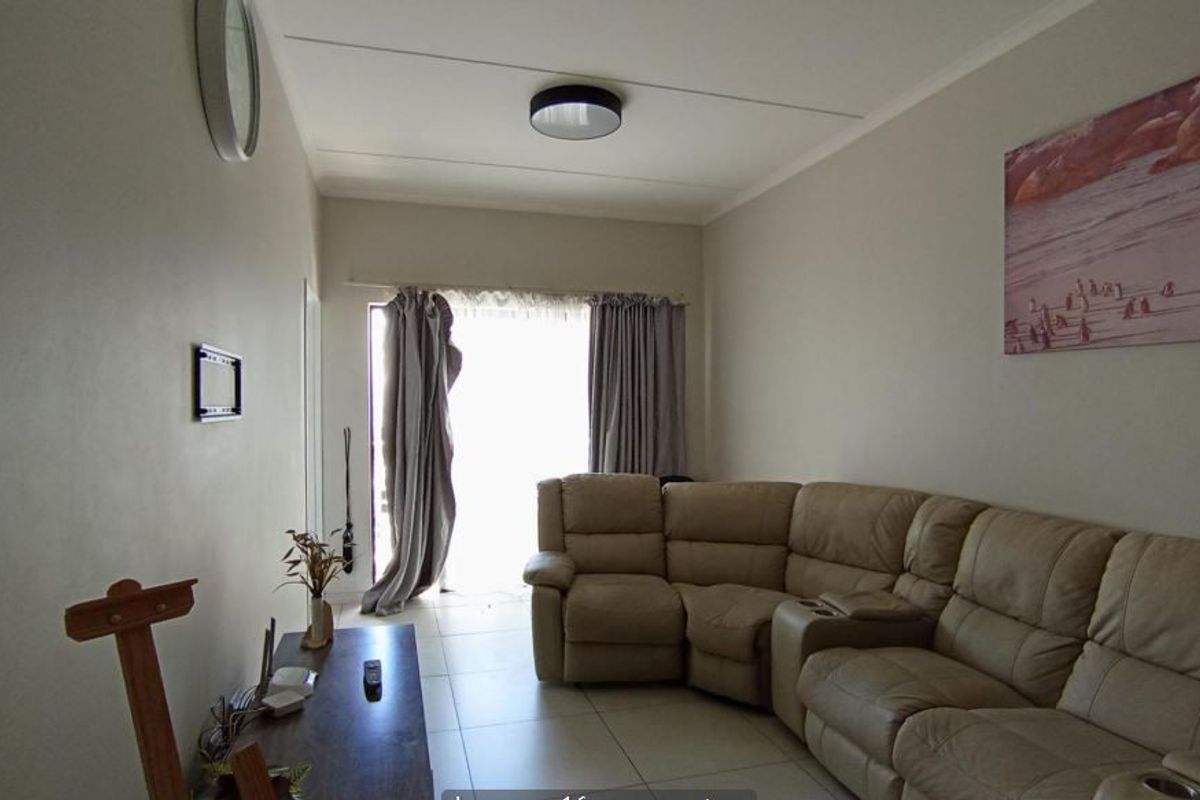 A comfortable living room featuring neutral tiled flooring and a sliding glass door that provides access to the outdoor area.