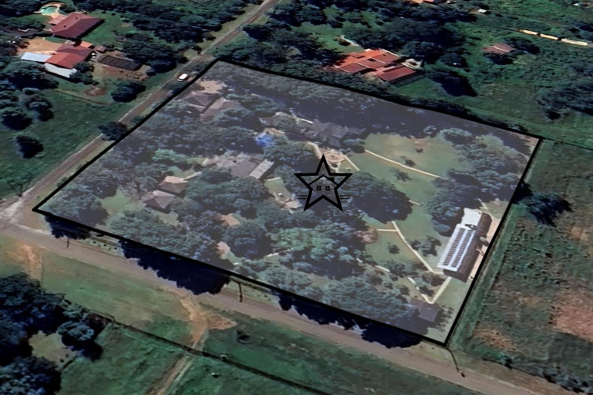 An aerial view of the property grounds, highlighting the expansive land, mature trees, and existing building structures within the highlighted boundary.