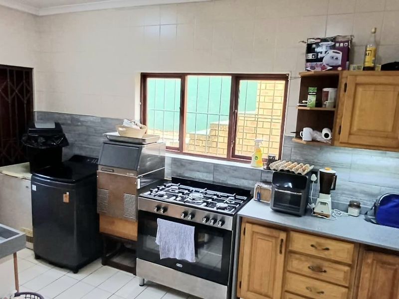 A functional kitchen featuring wooden cabinetry, a gas stove with oven, tiled splashbacks, and tiled flooring, offering a practical layout for daily cooking.