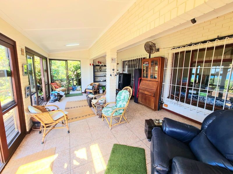 A covered patio area featuring tiled flooring, exposed brick walls, and large sliding glass doors providing access to the outdoor space.