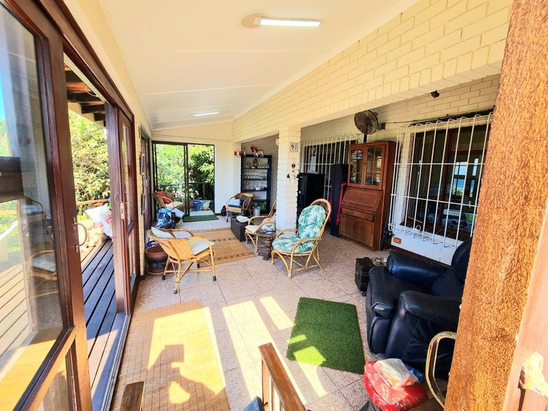 A covered patio area featuring tiled flooring, exposed brick walls, and sliding glass door access to the main living space.