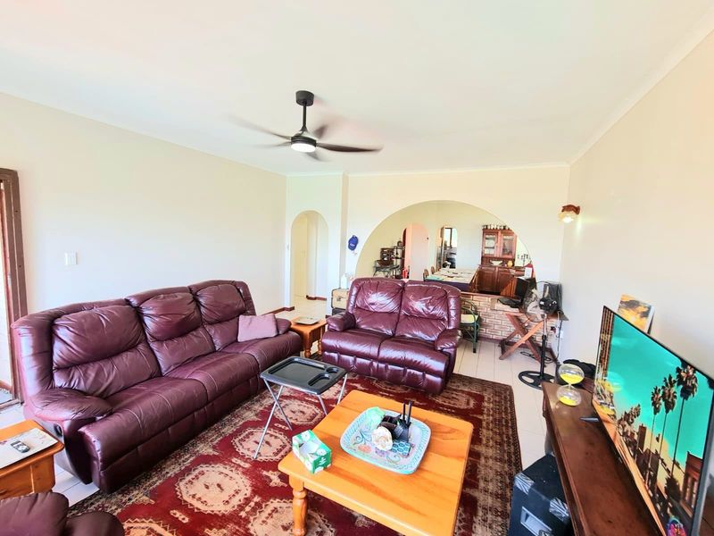 Open plan living area featuring tiled flooring, a ceiling fan, and a distinctive arched opening leading to the dining and kitchen space.