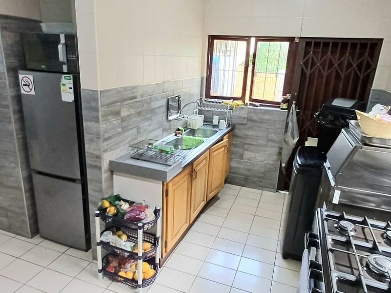 A functional kitchen featuring tiled flooring, built-in cabinetry, a double sink, and a tiled backsplash, providing a practical workspace for daily cooking.