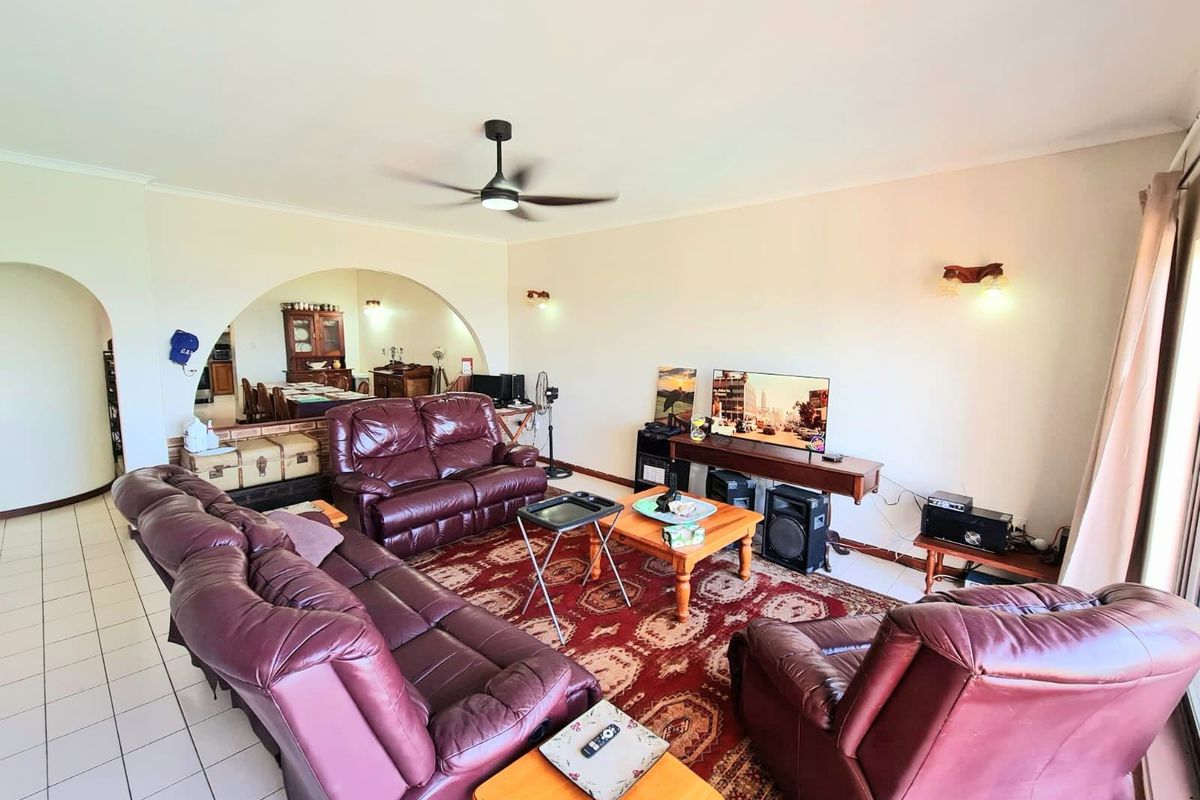 Spacious living room featuring tiled flooring, a ceiling fan, and a distinctive architectural archway leading to the adjacent dining area.