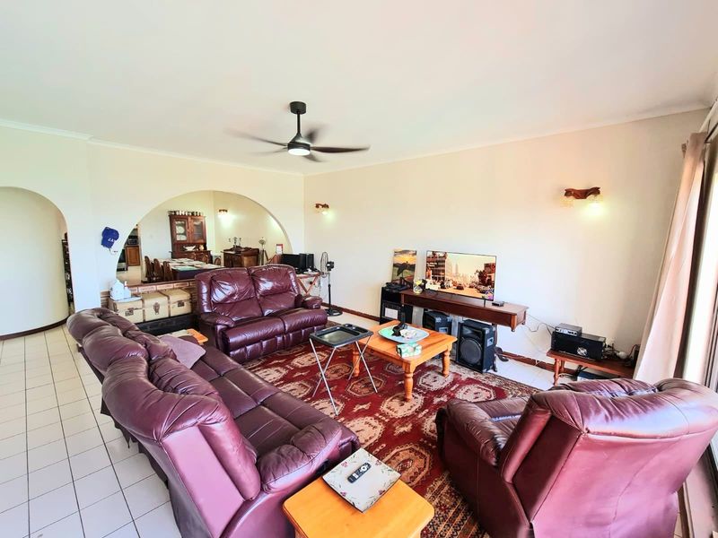 Spacious living room featuring tiled flooring, a ceiling fan, and a distinctive architectural archway leading to the adjacent dining area.