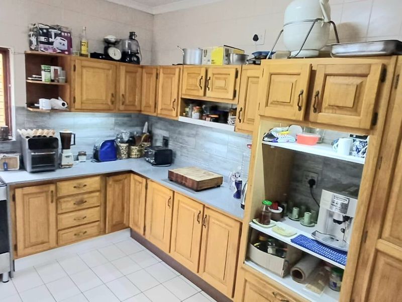 A functional kitchen featuring wooden cabinetry, a gas stove, tiled backsplash, and tiled flooring, offering a classic layout with ample storage space.