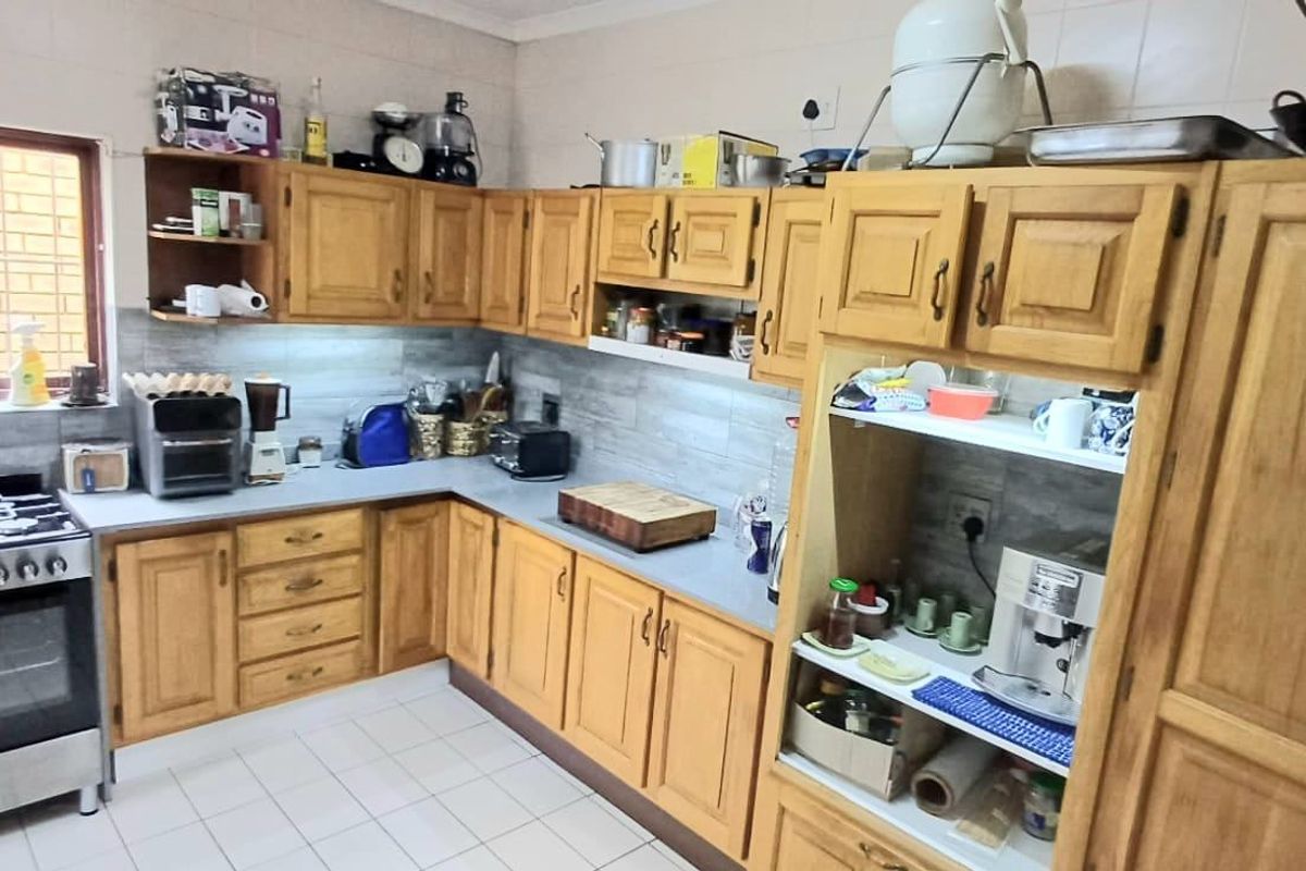 A functional kitchen featuring wooden cabinetry, a gas stove, tiled backsplash, and tiled flooring, offering a classic layout with ample storage space.