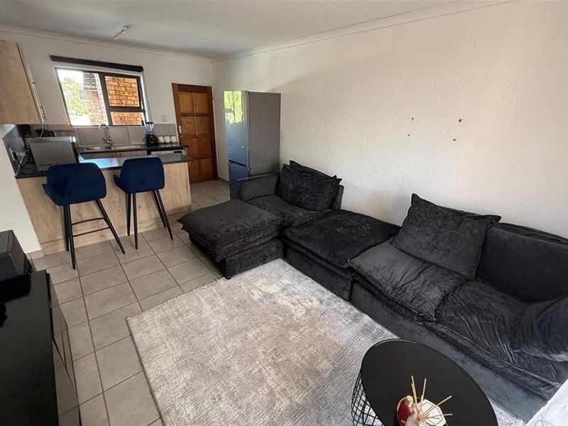 Open-plan living area featuring a compact kitchen with breakfast counter and tiled flooring throughout.